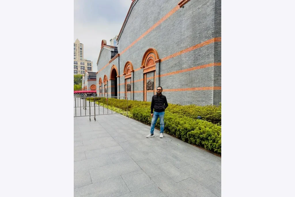 Dr. Shaikh Salman Salam outside a gray brick building with arched details.