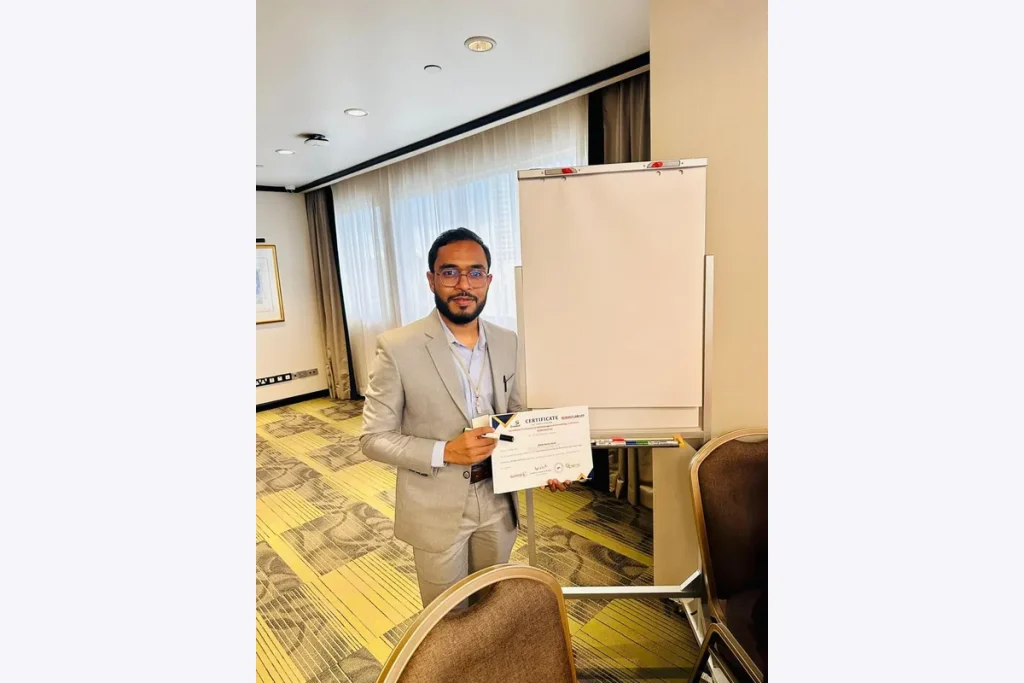 Dr. Shaikh Salman Salam holding a certificate beside a presentation board.